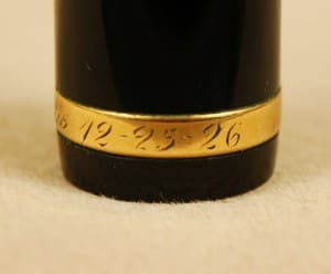 Black cylinder with engraved gold band date.