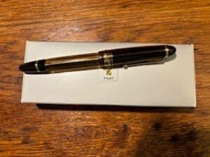 Fountain pen on white box, wooden table.