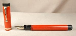 Red fountain pen with cap on side.