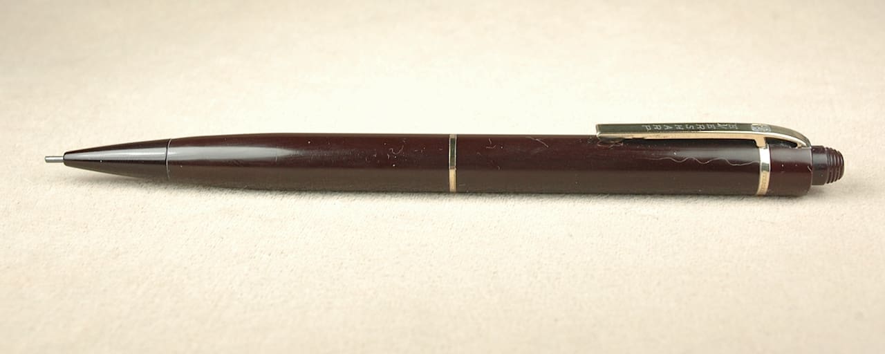 Brown mechanical pencil on beige background.