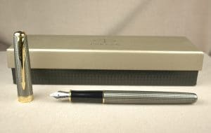 Silver fountain pen with case on table.