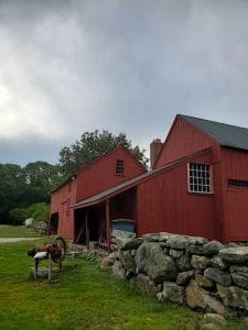 Red barn with stone wall and wagon.