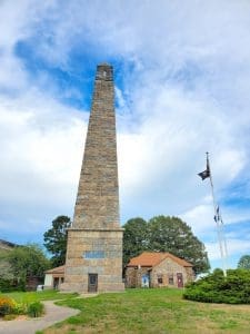 Stone obelisk tower with surrounding greenery.