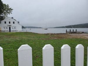 White fence by a lake with boathouse.