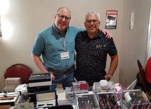 Two men standing behind a table display.