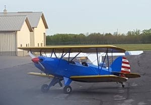 Blue biplane parked near hangar.