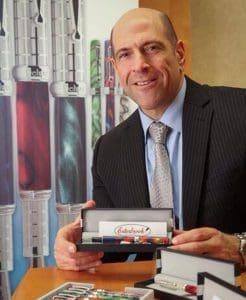 Man holding boxed pens, standing by display.