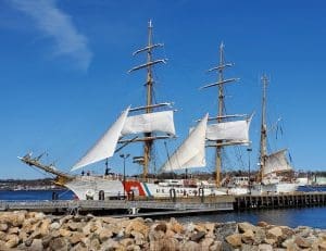 Tall ship docked at a sunny harbor.