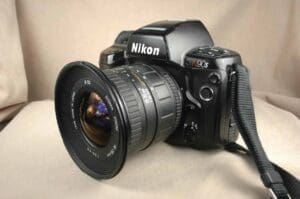 A Nikon DSLR camera with a wide-angle lens on a beige surface.
