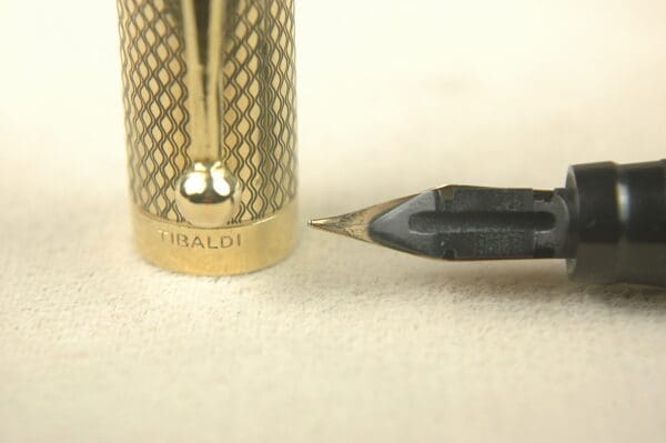 Gold pen cap and black nib close-up.