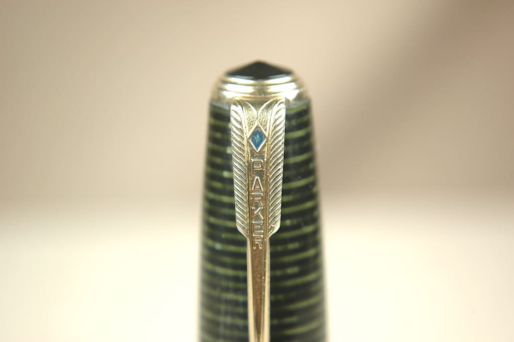 Close-up of a green fountain pen cap with a detailed gold clip.
