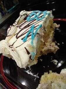Partially eaten cake with white frosting and blue decorations.