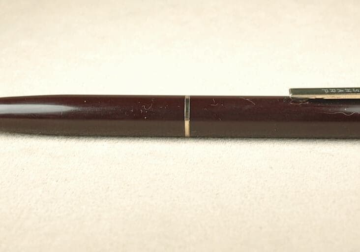 Brown mechanical pencil on beige background.